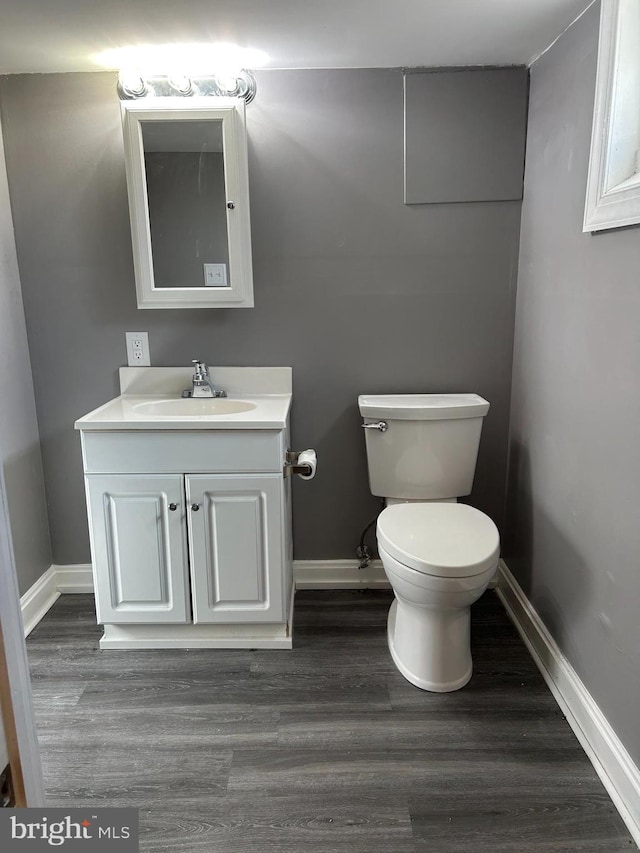 bathroom featuring toilet, vanity, and hardwood / wood-style floors