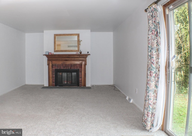 unfurnished living room featuring carpet flooring and a brick fireplace