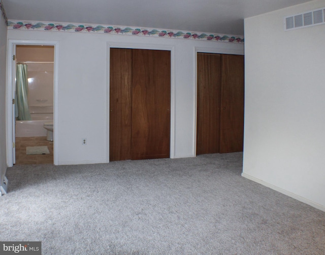 unfurnished bedroom featuring ensuite bathroom and carpet floors