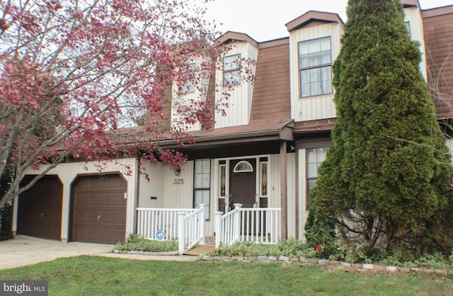 view of front of home with a front yard, a garage, and a porch