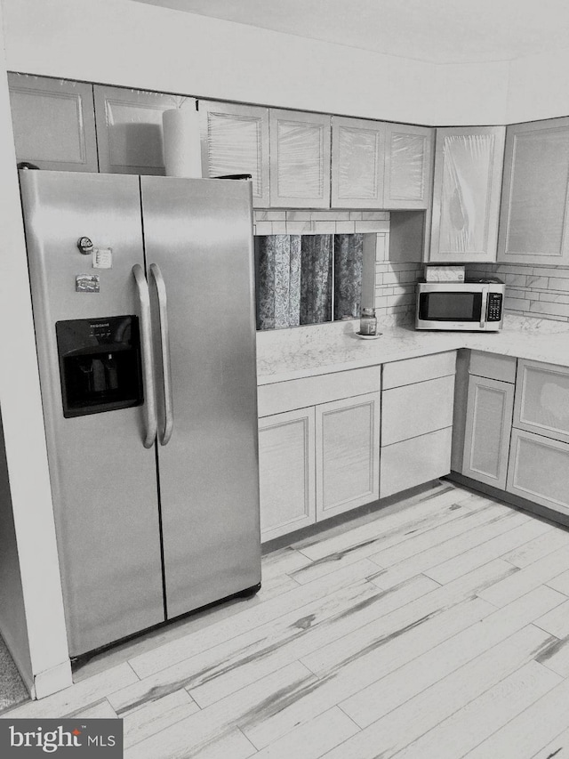 kitchen featuring light hardwood / wood-style floors, stainless steel appliances, backsplash, and gray cabinets