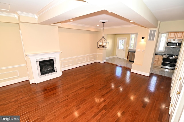 unfurnished living room with a chandelier, dark hardwood / wood-style floors, and crown molding