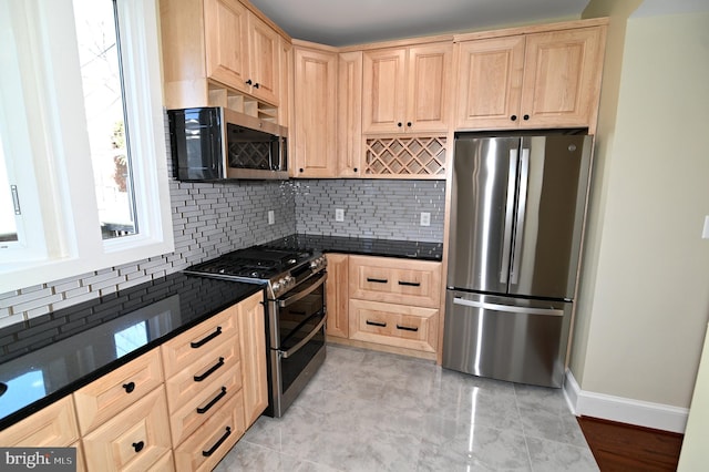 kitchen with stainless steel appliances, light brown cabinetry, dark stone countertops, and backsplash