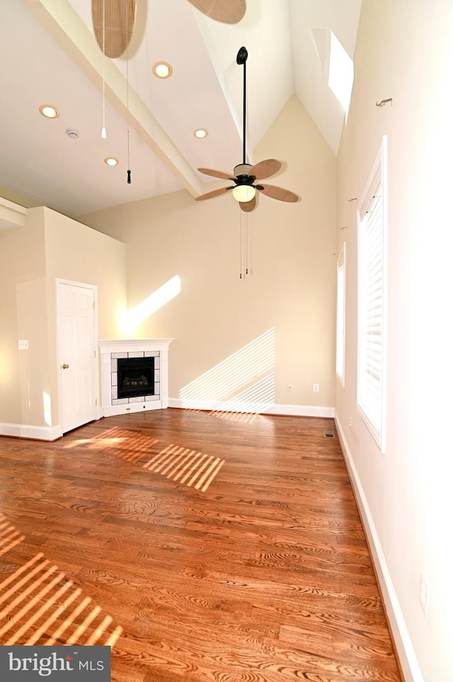 unfurnished living room featuring high vaulted ceiling, hardwood / wood-style flooring, ceiling fan, and beam ceiling