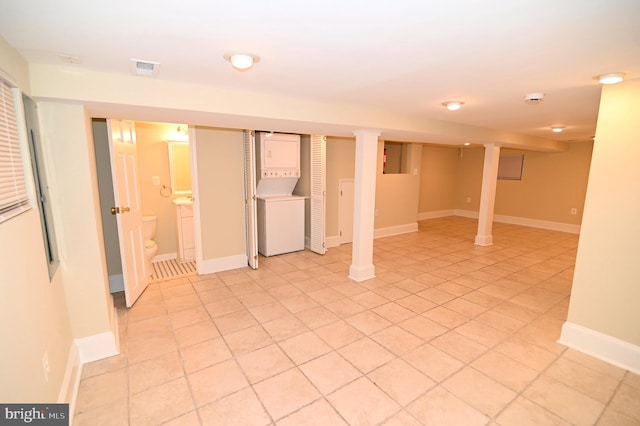 basement featuring light tile patterned flooring and stacked washer and clothes dryer