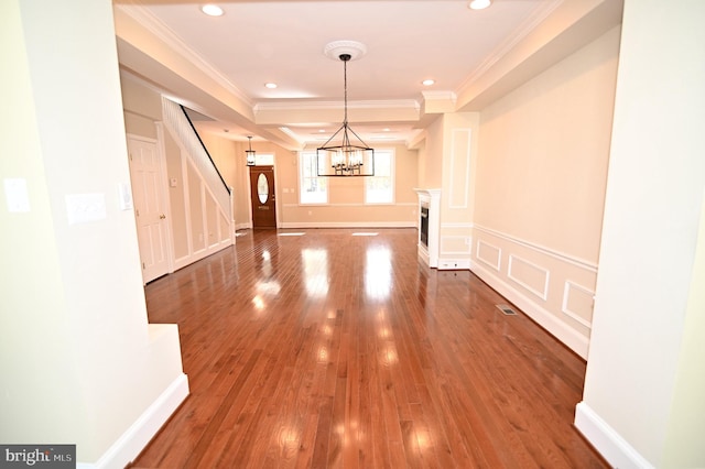 foyer featuring an inviting chandelier, wood-type flooring, and ornamental molding