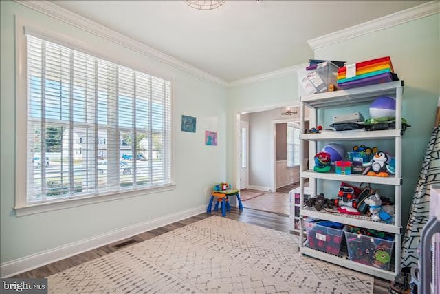 recreation room with ornamental molding and hardwood / wood-style floors