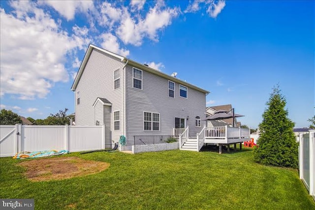 rear view of house with a deck and a lawn