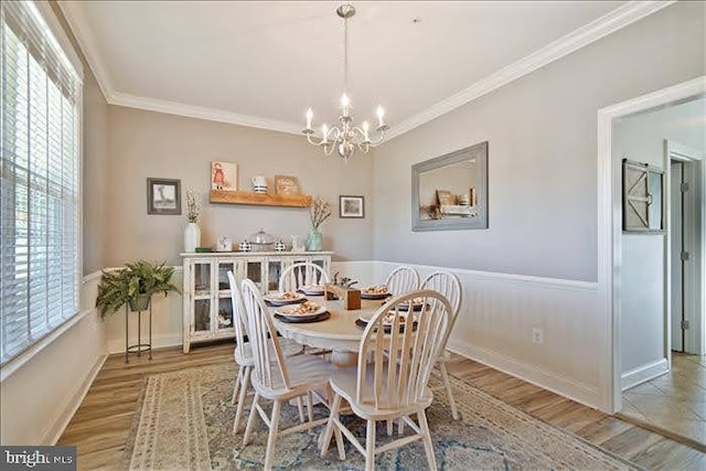 dining space with crown molding, a notable chandelier, and light wood-type flooring