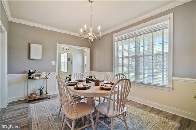 dining area featuring crown molding, hardwood / wood-style flooring, a wealth of natural light, and a chandelier