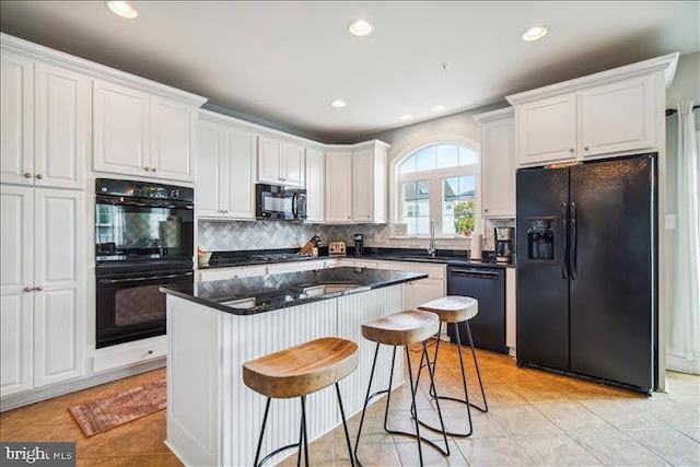 kitchen featuring light tile patterned flooring, white cabinets, black appliances, and backsplash