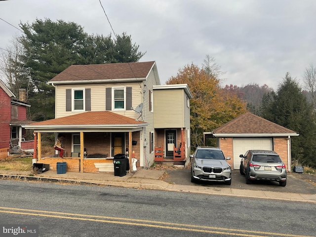 view of property with covered porch, a garage, and an outdoor structure