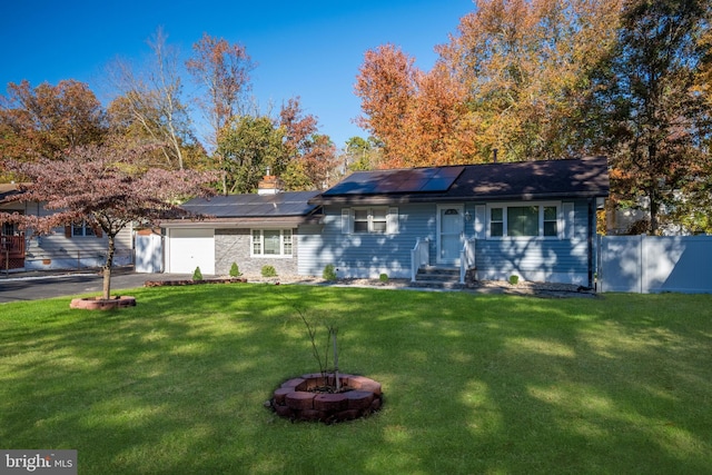 ranch-style house with a front yard, a fire pit, and solar panels