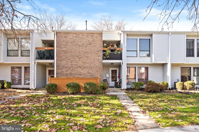 view of property with a balcony and a front yard