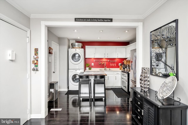 kitchen featuring white cabinets, ornamental molding, dark hardwood / wood-style floors, and stacked washer / dryer