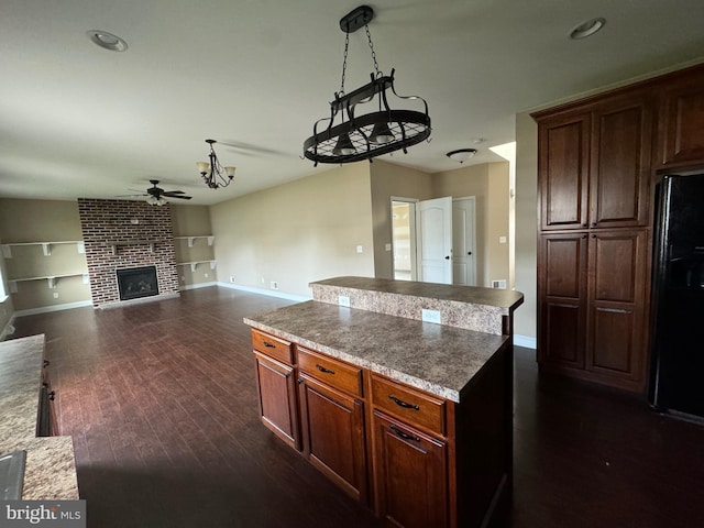 kitchen featuring black refrigerator, pendant lighting, dark hardwood / wood-style flooring, a fireplace, and ceiling fan