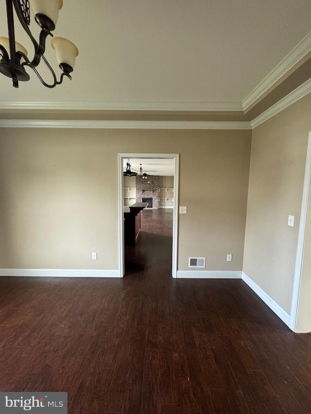 empty room featuring crown molding, a chandelier, and dark hardwood / wood-style flooring