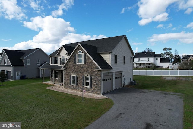 view of front of property featuring central air condition unit, a front yard, and a garage