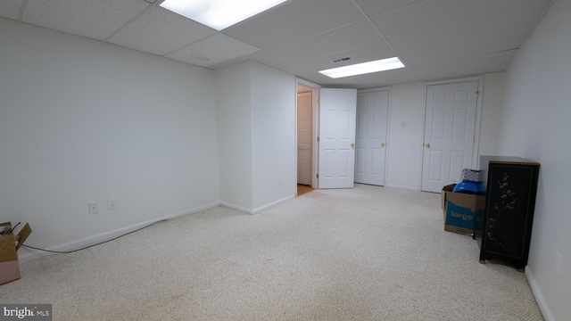 basement with light colored carpet and a paneled ceiling