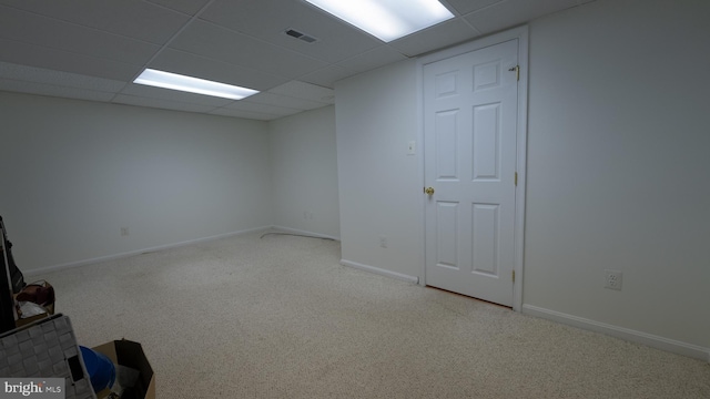 basement featuring light carpet and a paneled ceiling