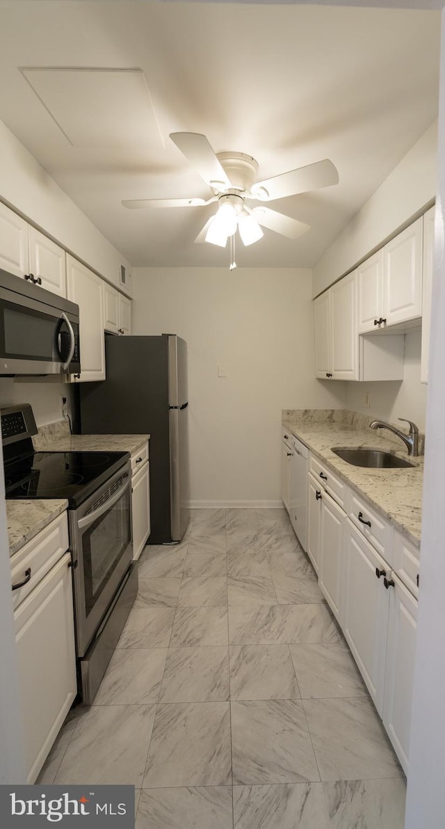 kitchen with light stone countertops, appliances with stainless steel finishes, sink, ceiling fan, and white cabinets