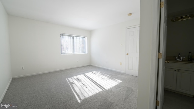 unfurnished bedroom featuring sink, light carpet, a closet, and ensuite bath