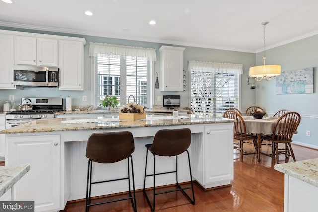 kitchen with white cabinetry, appliances with stainless steel finishes, hanging light fixtures, a center island, and dark hardwood / wood-style flooring