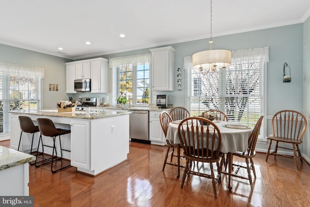 kitchen featuring appliances with stainless steel finishes, decorative light fixtures, dark hardwood / wood-style flooring, white cabinets, and a center island