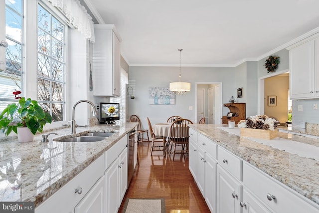 kitchen featuring sink, ornamental molding, light stone countertops, hanging light fixtures, and white cabinets