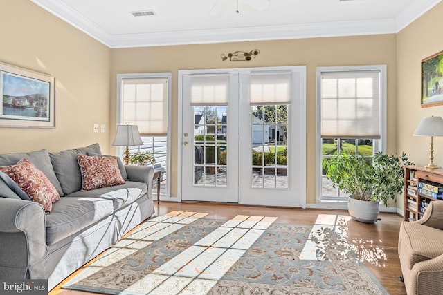 living room featuring a wealth of natural light, light wood-type flooring, and ornamental molding