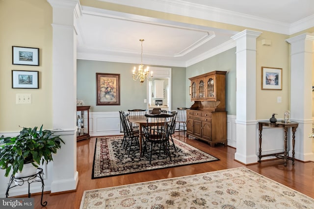 dining area with a chandelier, hardwood / wood-style floors, ornate columns, and crown molding