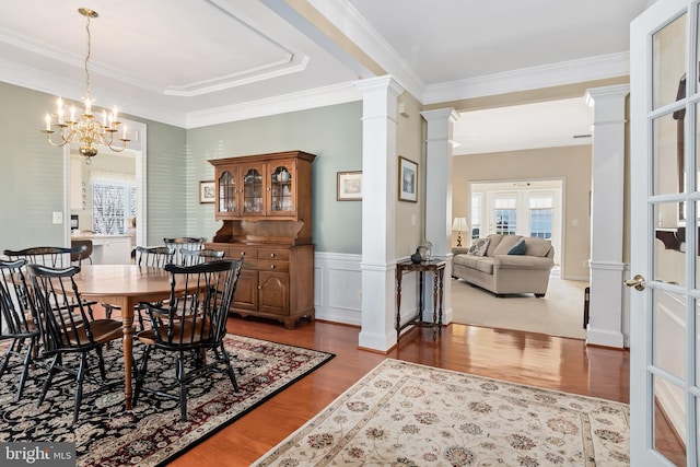 dining room with french doors, ornamental molding, a notable chandelier, ornate columns, and hardwood / wood-style flooring