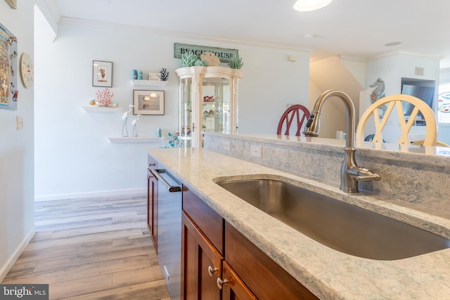 kitchen featuring crown molding, stainless steel dishwasher, sink, and light wood-type flooring