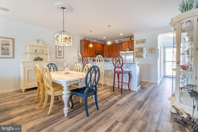 dining space featuring wood-type flooring and ornamental molding