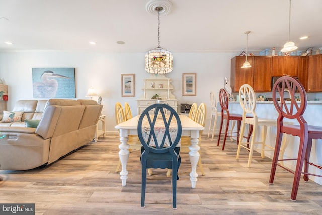 dining space featuring light hardwood / wood-style floors, crown molding, and an inviting chandelier