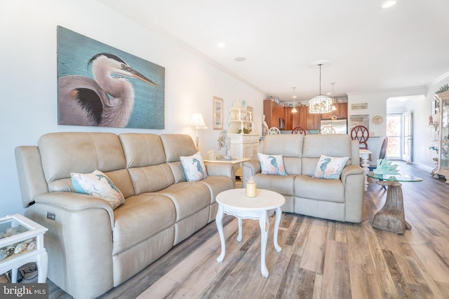 living room featuring a chandelier, crown molding, and light wood-type flooring