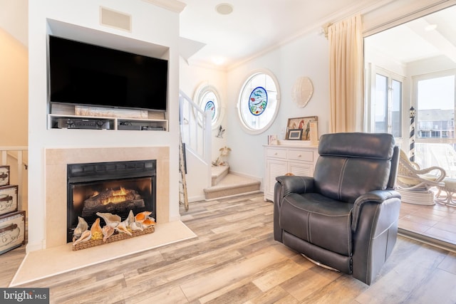 living area with crown molding and light wood-type flooring