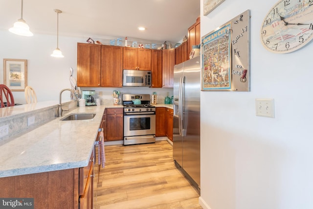 kitchen featuring stainless steel appliances, sink, light hardwood / wood-style floors, crown molding, and decorative light fixtures