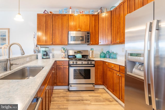 kitchen with stainless steel appliances, ornamental molding, sink, and light wood-type flooring