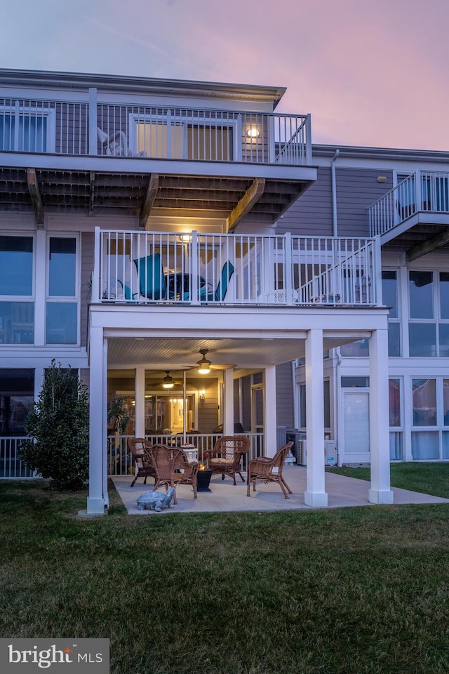 back house at dusk featuring a yard, a patio area, and ceiling fan