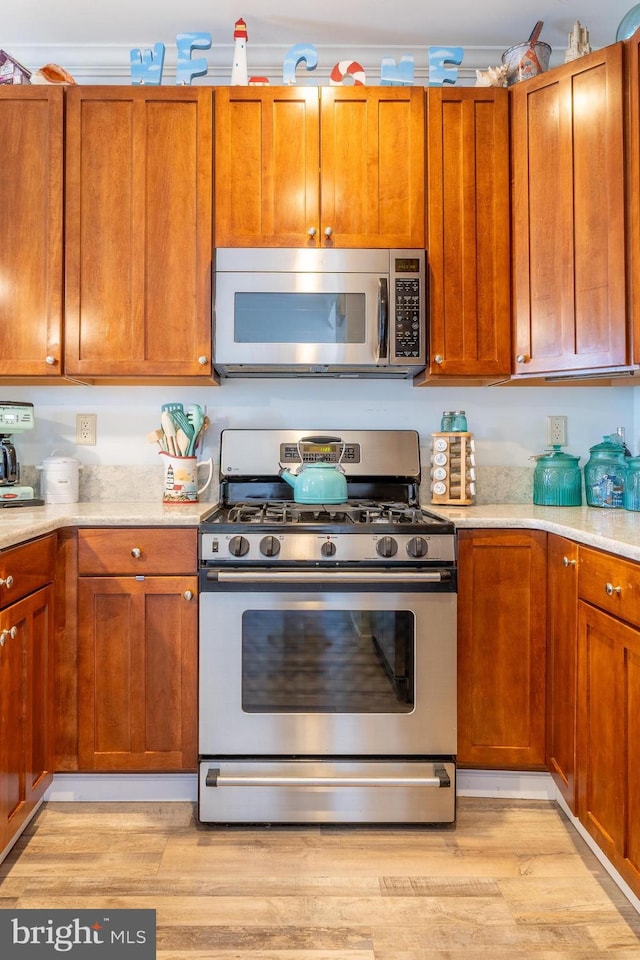 kitchen with light hardwood / wood-style floors, stainless steel appliances, and crown molding