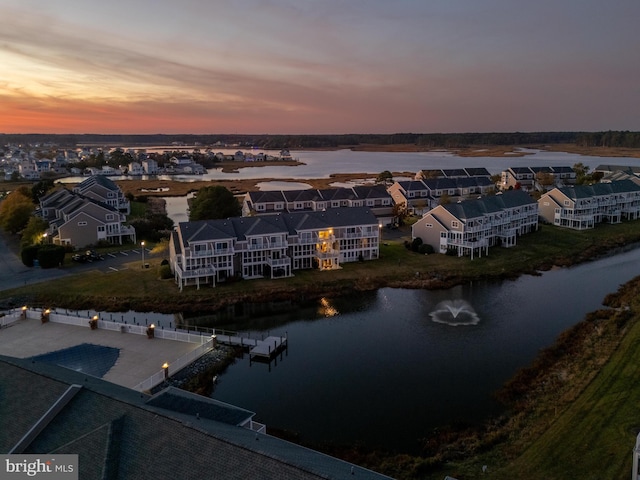 aerial view at dusk featuring a water view