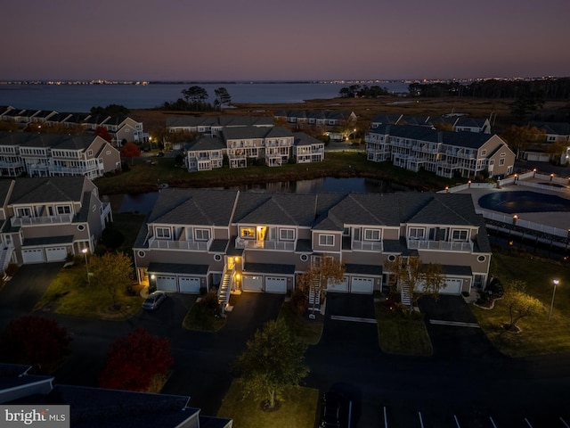 aerial view at dusk featuring a water view