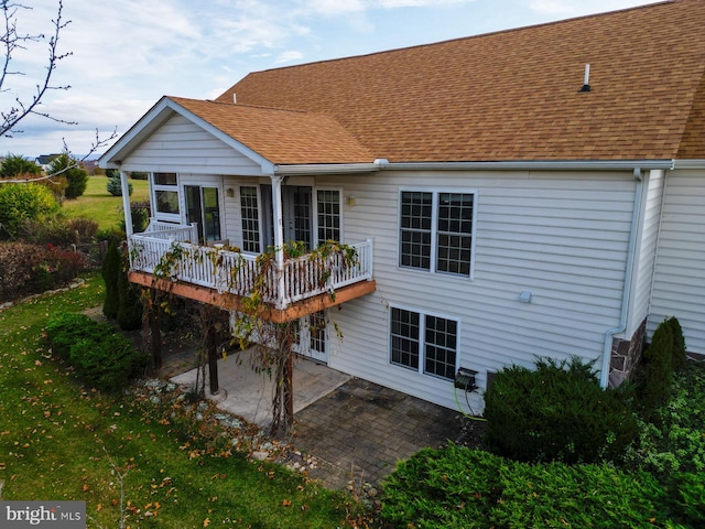 rear view of house featuring a wooden deck and a patio area