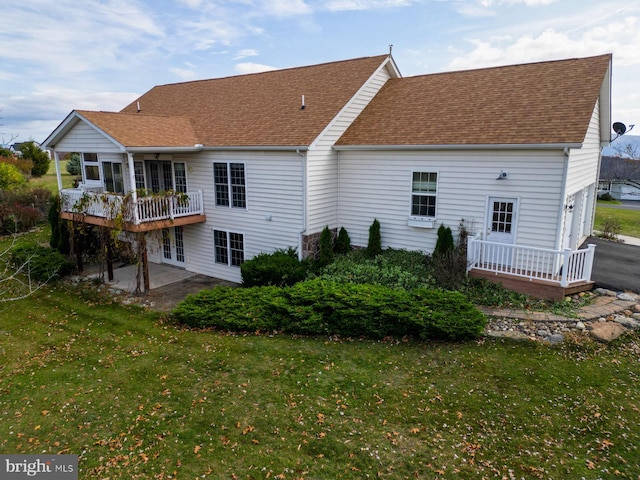 rear view of house with a balcony and a yard