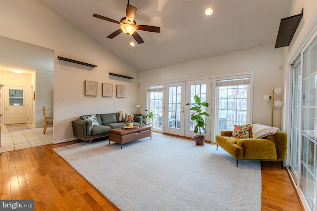 living room featuring french doors, light wood-type flooring, ceiling fan, and high vaulted ceiling