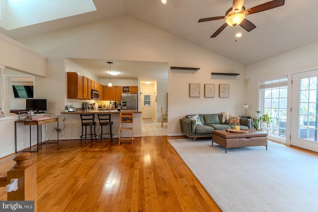 living room with high vaulted ceiling, light hardwood / wood-style flooring, and ceiling fan