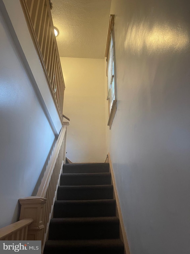 staircase featuring a textured ceiling