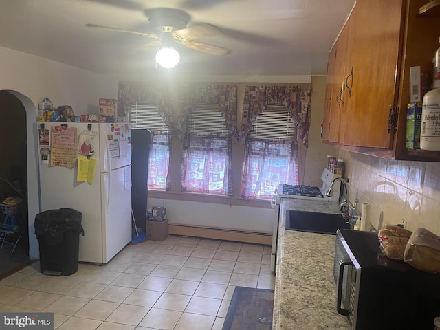 kitchen featuring light tile patterned flooring, a baseboard heating unit, ceiling fan, tasteful backsplash, and white fridge