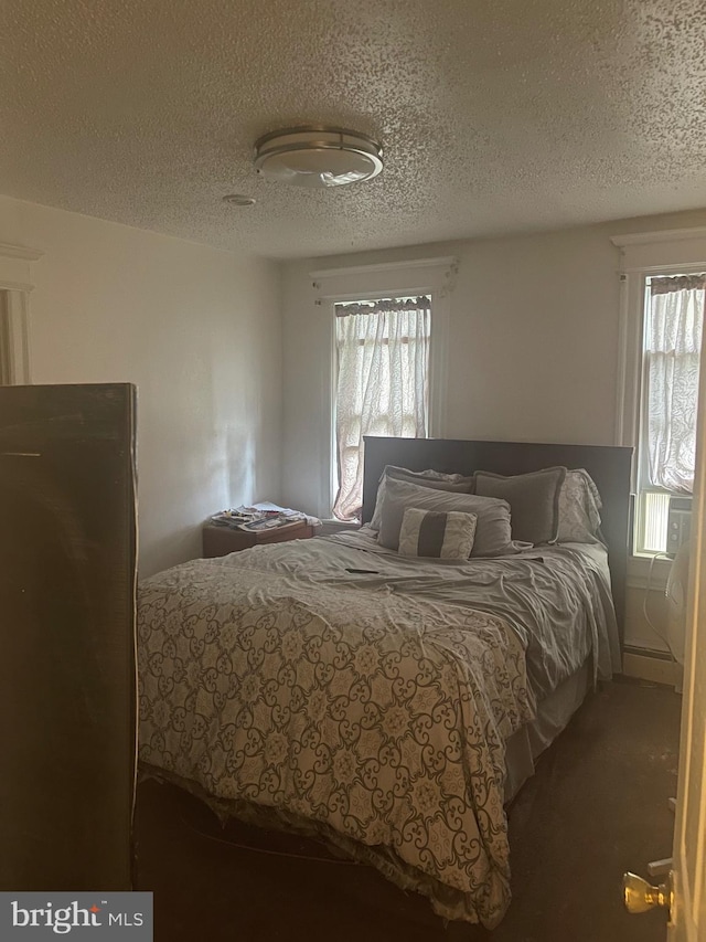 bedroom with a textured ceiling and dark carpet